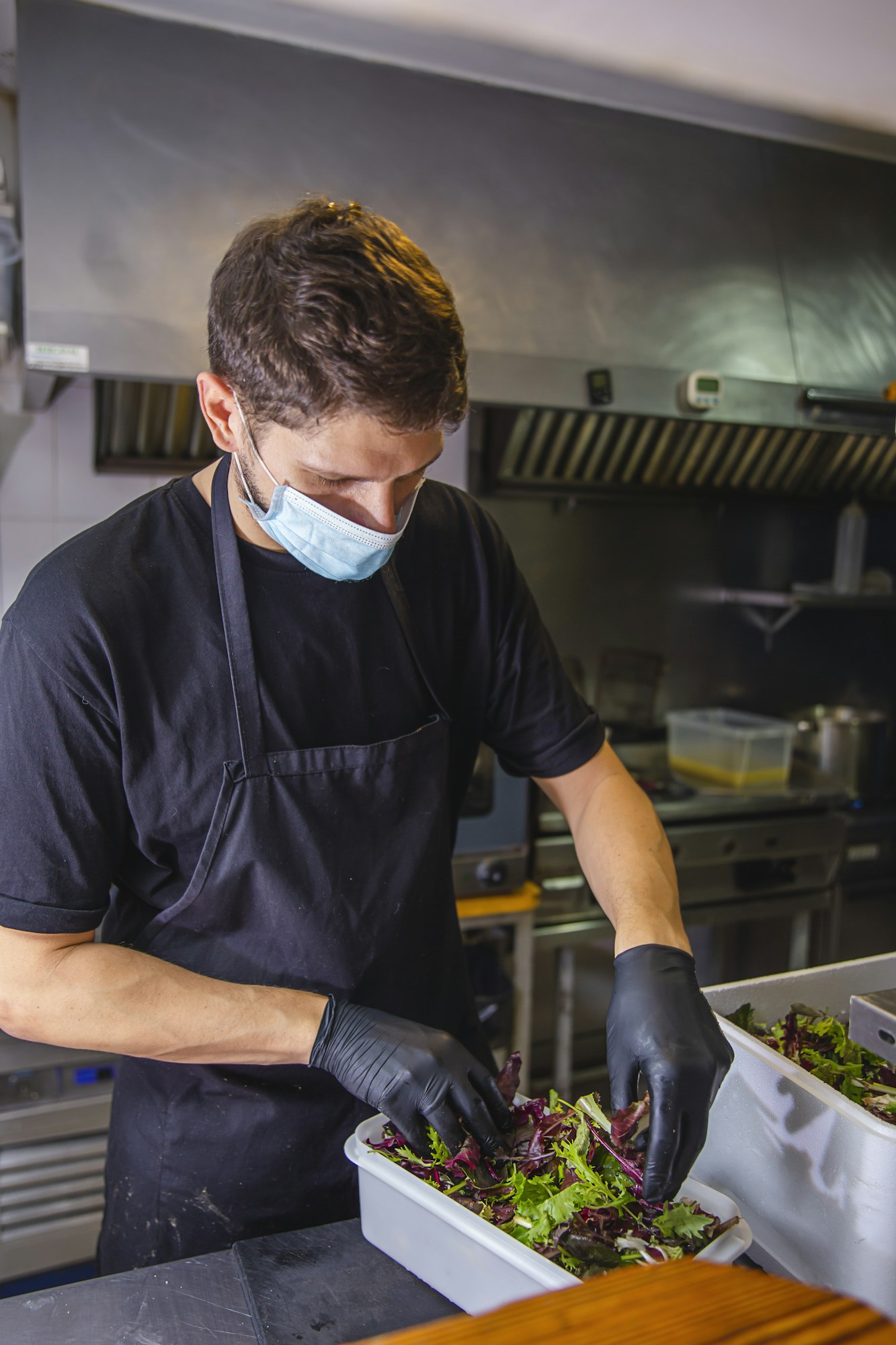 Cook preparing food with safety and hygiene measures in a restaurant kitchen