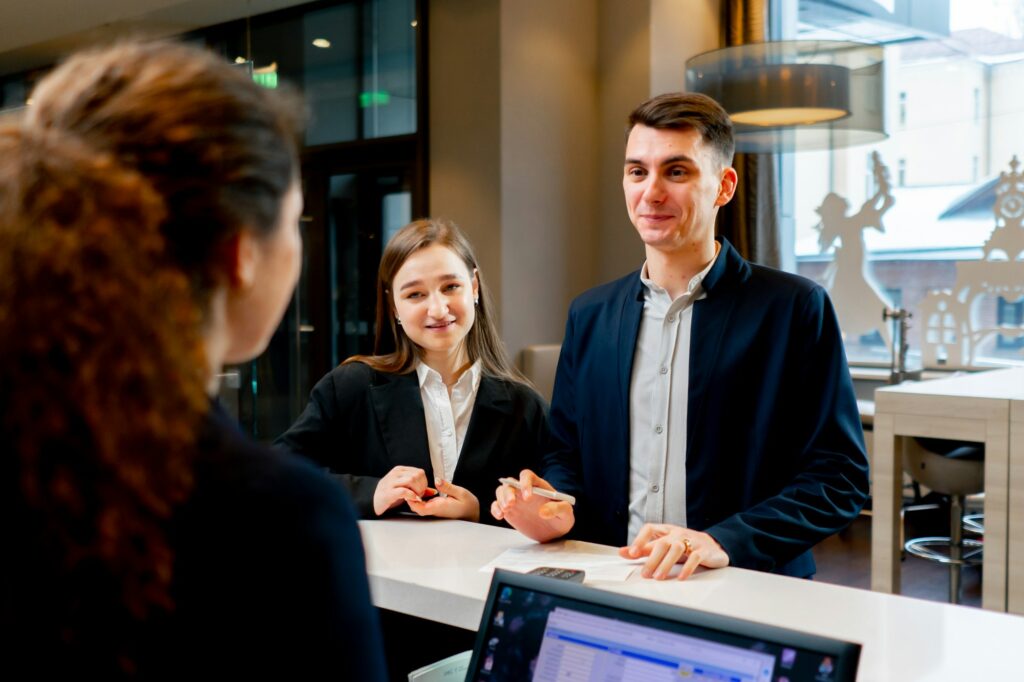 The receptionist at the counter meets guests with luggage in the hotel business travel hospitality